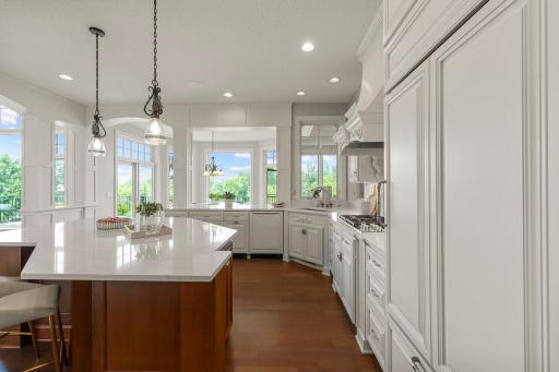Bright kitchen with large center island, gas cooktop, and custom cabinetry. Oversized windows provide natural light and views of the backyard and screened porch.