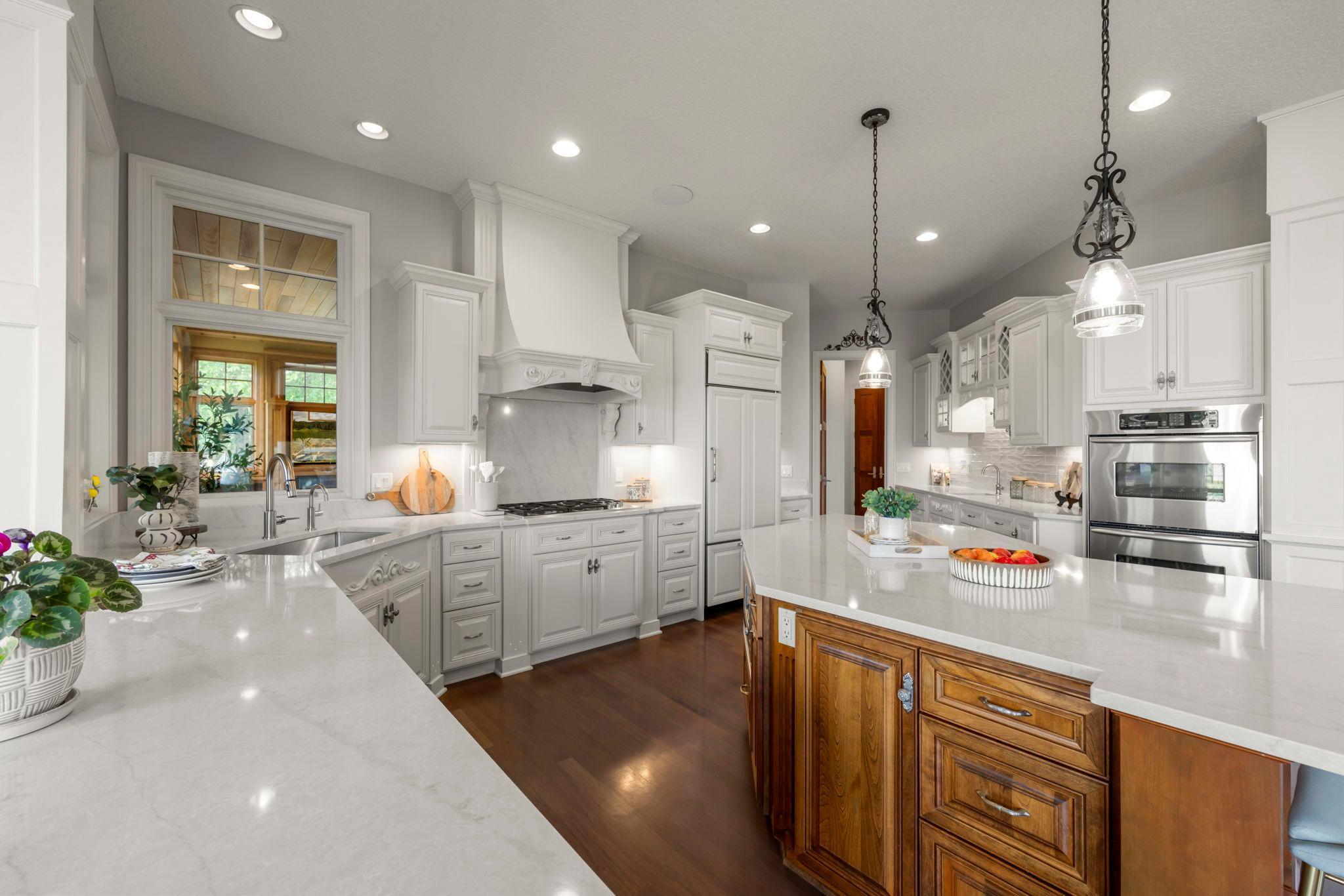 Spacious kitchen with professional-grade appliances, oversized island, and rich wood accents. Thoughtful layout connects seamlessly to the dining and living areas, with expansive windows bringing in natural light and views. Ideal for everyday living!