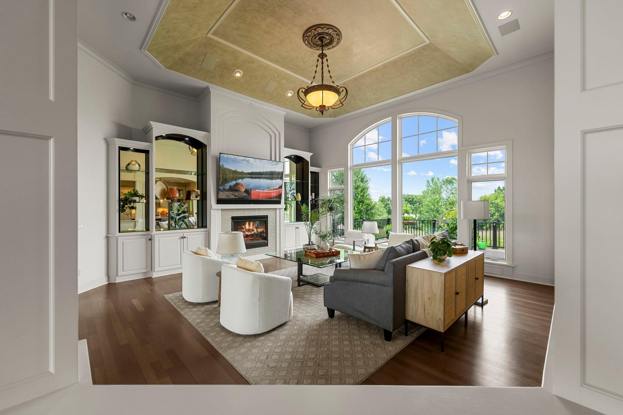 The great room offers tall ceilings, a gas fireplace and a wall of windows that fill the space with natural light and frame the private backyard view. Ideal for relaxed gatherings or quiet evenings at home.