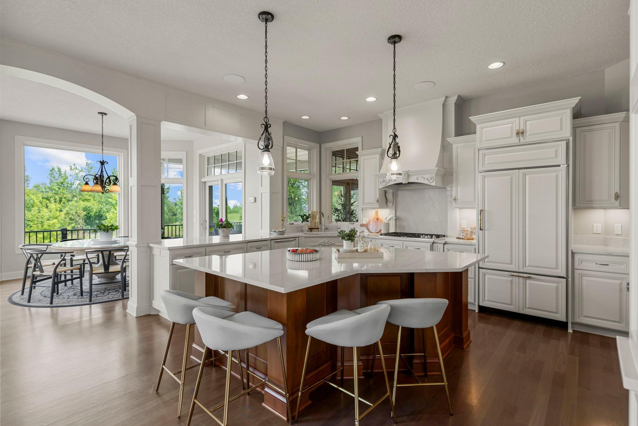 Spacious kitchen with large center island, prep sink, double ovens, and custom cabinetry with glass display and wine storage. Open sightlines to the great room and dining areas offer ideal flow for everyday living and entertaining.