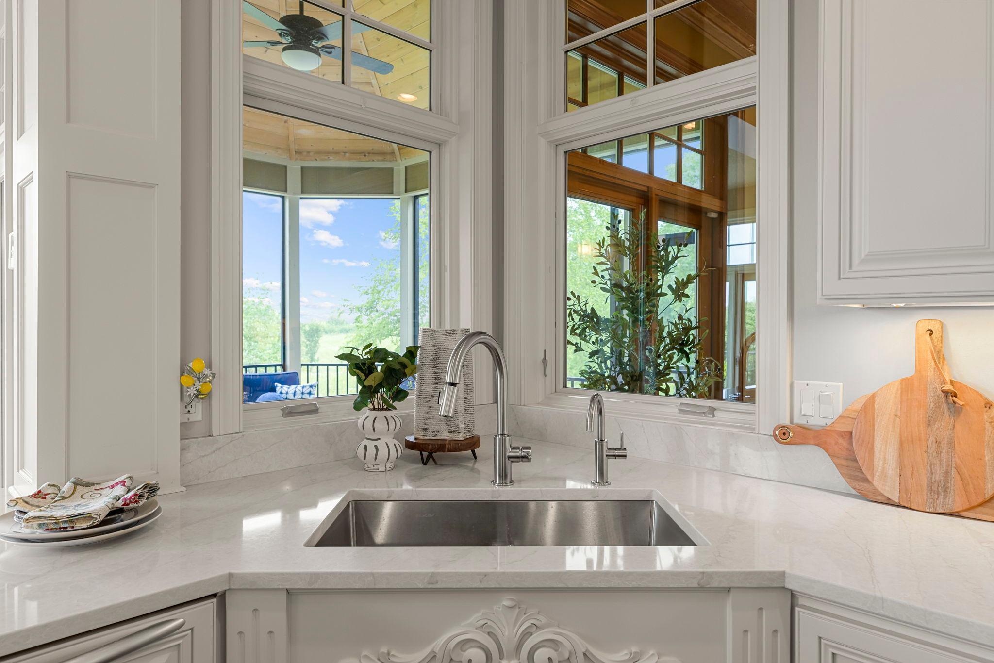 Enjoy serene views into the screened porch and backyard from the kitchen sink. Oversized windows fill the space with natural light, creating a bright and connected feel between indoor and outdoor living.