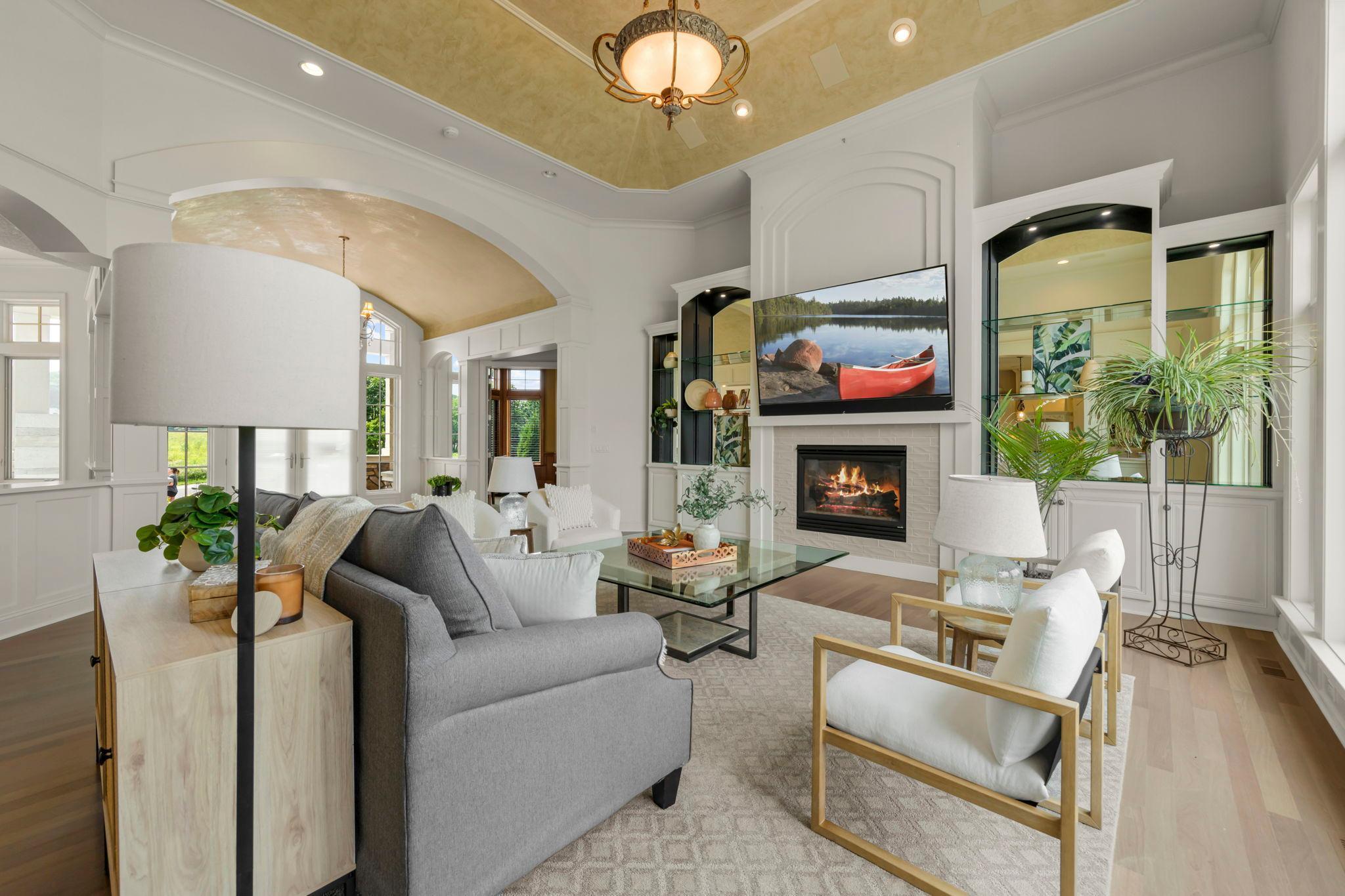 Inviting great room with gas fireplace and custom built-ins. Beautifully framed by arched openings and large windows that capture natural light and expansive backyard views- ideal for relaxing or entertaining in style.