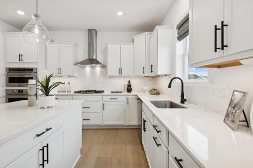 (Photo of a decorated model, actual homes finishes will vary) Welcome to the Lewis! This spacious kitchen features a large center island, quartz countertops, LVP floors, stainless appliances and more.