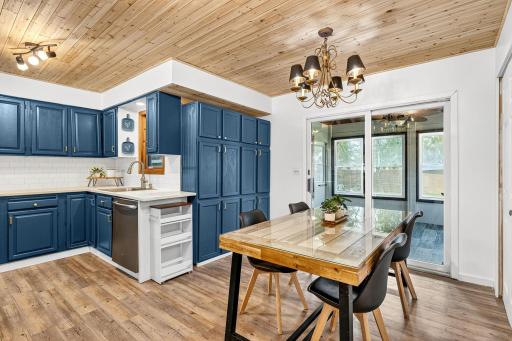 Open concept view from the dining area to the kitchen, showcasing modern updates and abundant storage. The natural wood ceiling unites both spaces beautifully.