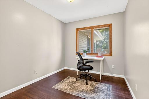 Versatile bedroom or home office space with warm wood trim and a large window overlooking the backyard.
