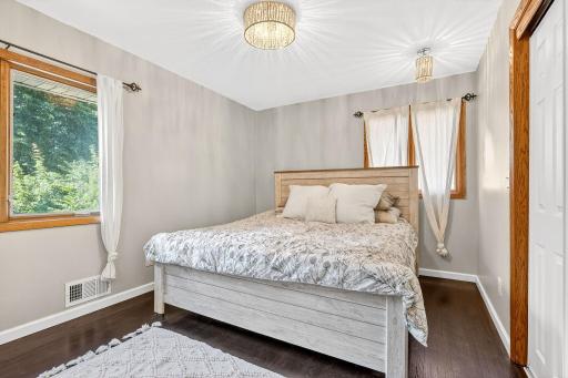 Bright and inviting primary bedroom featuring two large windows and hardwood floors.