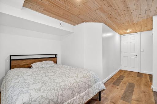 Lower level bedroom #5 as LVP floors, a natural wood ceiling and a look-out window.