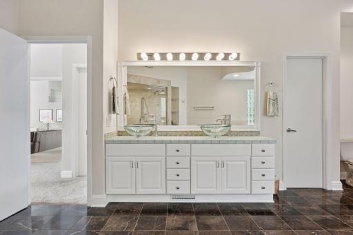 The enameled vanity offers two vessel sinks and tiled countertops.