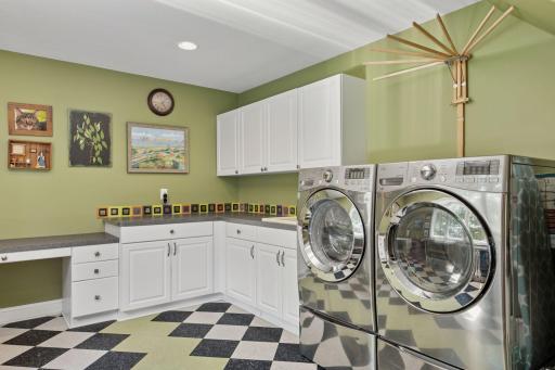 Located on the main level is the Laundry Room - with a checkerboard floor, custom cabinetry and a built-in planning desk, this space is sure to keep you organized and help make doing laundry a breeze! The LG washer sits atop a pedestal washer.
