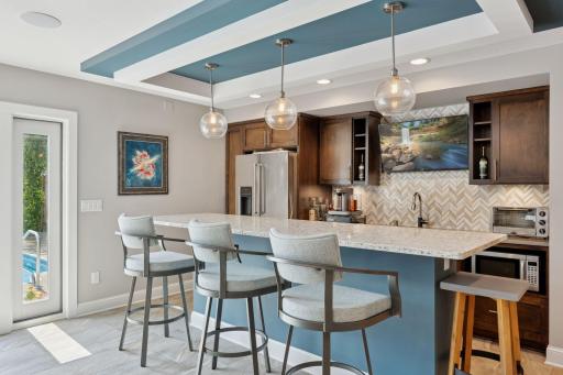 The well-equipped wet bar features custom cabinetry, a Fischer and Paykel dishwasher drawer and KitchenAid refrigerator.