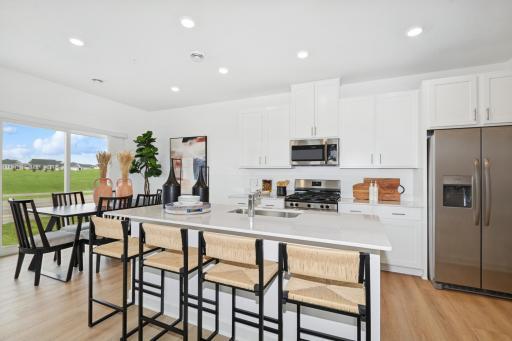 (Photo of a decorated model, actual homes finishes will vary) The stunning kitchen features a large center island, quartz countertops, LVP floors, stainless appliances, and more!
