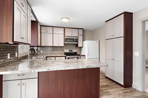 Updated Kitchen with stainless steel appliances, tile backsplash, breakfast bar, pantry cabinet, ceiling fan and Freshly Painted Cabinets