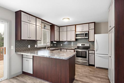 Updated Kitchen with stainless steel appliances, tile backsplash, breakfast bar, pantry cabinet, ceiling fan and Freshly Painted Cabinets