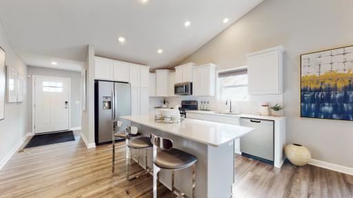 Large dream kitchen anchored by an large kitchen island. Stainless appliances, quartz countertops, LVP wood floors and more! (Photo of decorated model, actual home's finishes may vary slightly)