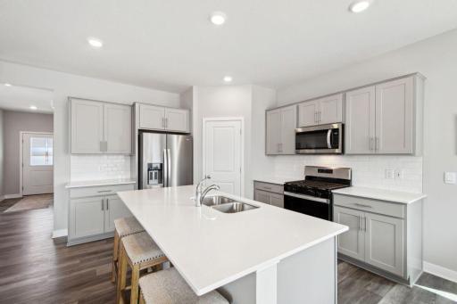 A stunning kitchen layout, all while remaining remarkably functional: The quartz is endless, the sink is under-mounted, the range is gas, the micro-hood is vented to the exterior of the home! Photo of model home, color & options may vary.