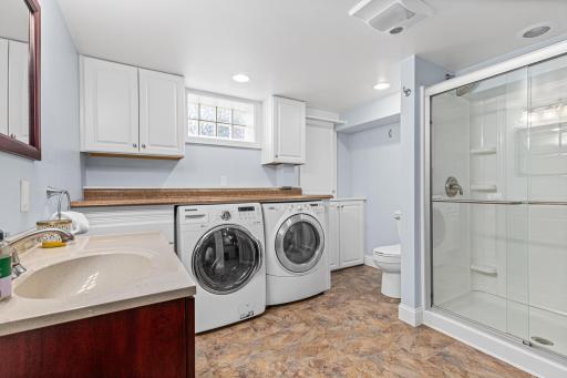 Large basement 3/4 bathroom also houses washer and dryer with folding counter and cabinetry