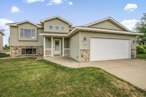 This lovely home features maintenance-free vinyl siding accented by stone, architectural shingles, a covered front entry and a spacious two-stall attached garage.