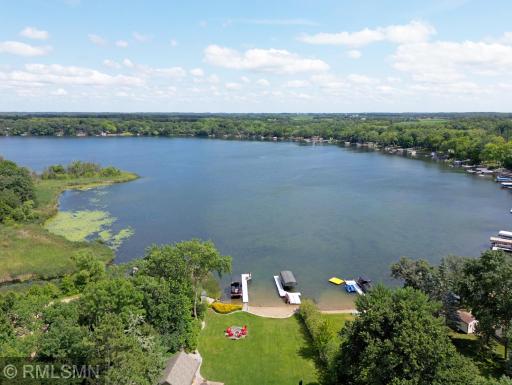An aerial view reveals the expansive yard and 86 feet of sandy, hard-bottom lakeshore, while mature trees on both sides provide an added layer of privacy.