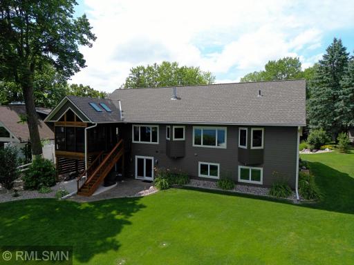 The lakeside of the home features two sliding walkout doors on the lower level that open to a covered patio, while the upper level boasts another sliding door leading to the four-season porch.