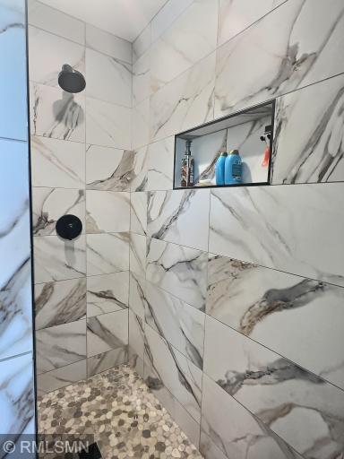 The primary walk-in shower features beautiful tilework and is designed without the need for a shower curtain or glass door, making cleaning effortless.