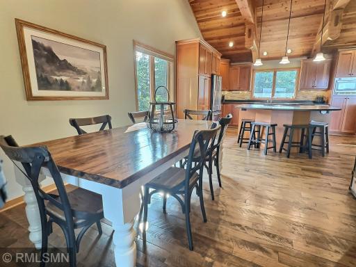 Hereâs a beautiful view of the open dining room and kitchen area. The combination of the flooring and vaulted beamed ceiling creates a warm and inviting space perfect for entertaining.