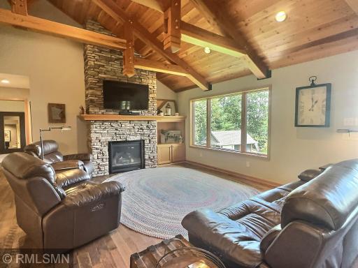 Relax by the gas fireplace, featuring a stone surround and a substantial mantel, in the spacious, light-filled living area. Picture windows showcase stunning views of the yard and lake, bringing the outdoors in.