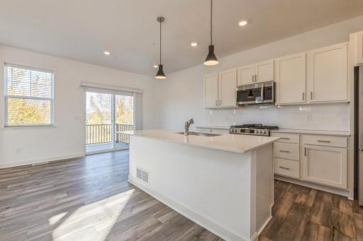 (Photo of an inventory home, actual homes finishes will vary) Spacious kitchen with a large center island, quartz counter tops, tile backsplash, pull-out trash/recycling cabinet, and slate appliances.