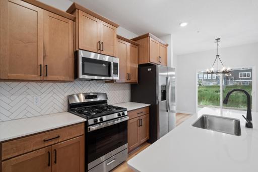 Cabinetry in cashew stain but actual has upgraded range and backsplash, plus the brushed gold hardware/fixtures. Picture is an example of layout.