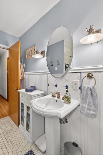 Brushed nickel wall sconces flank the large oval mirror above the pedestal sink.