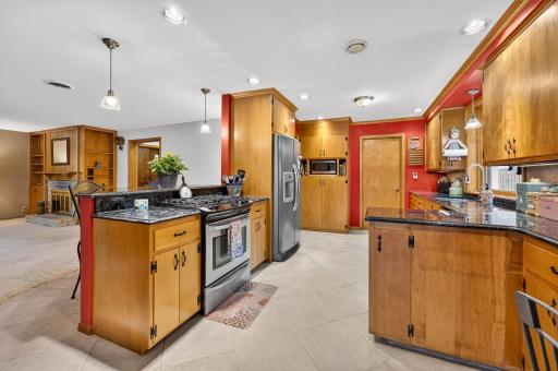 A granite topped island houses a stainless steel gas range.