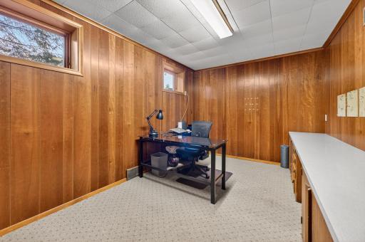 The den in the lower level has rich, warm tone wood paneled walls.