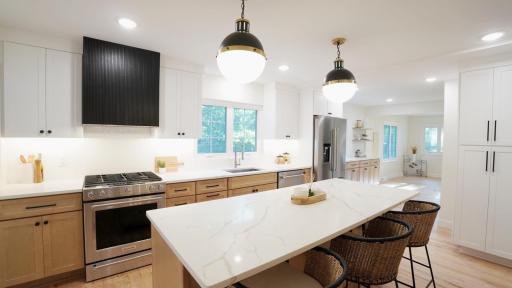 The expanded, brand new kitchen is everything modern, high end and welcoming. Entertain with custom soft-close cabinetry, quartz countertops, designer lighting, ample storage, an eye-catching, contemporary range hood and new KitchenAid appliances.