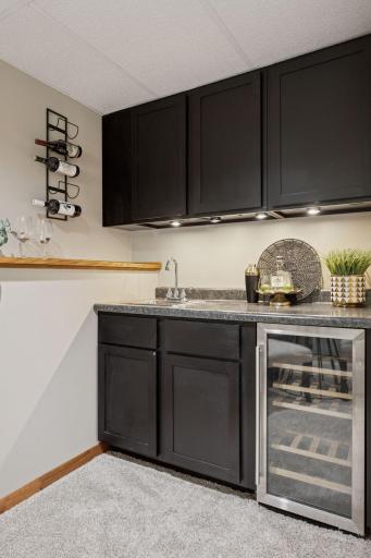 Lower level wet bar with beverage cooler and sleek stone countertops.
