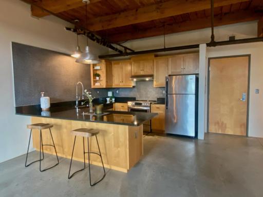 The large kitchen in this large, open loft features a matching stainless steel appliance package, coordinated industrial pendant lighting, and a huge peninsula with seating for at least four.