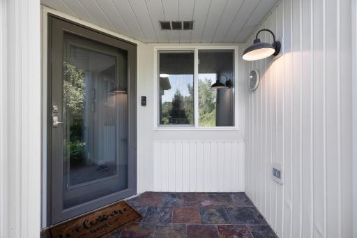 Stunning covered patio entrance with slate tile and gooseneck barn light.