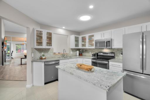 Incredible white enameled eat-in kitchen with glass accent cabinet doors. Solar tube light shown.
