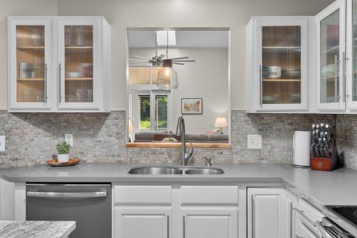 Attractive tiled backsplash, hard surface countertop, pendant light over the sink and cut out overlooks the dining room and living room.