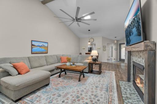 Vaulted living room with ceiling fan and fireplace.