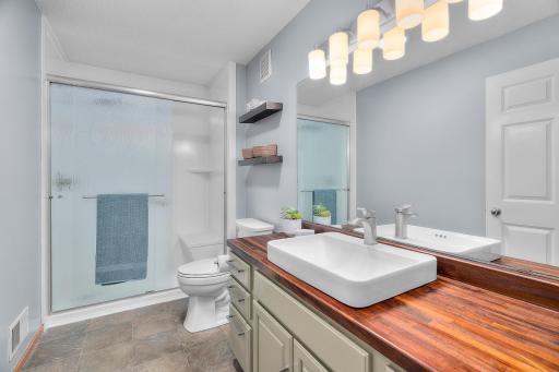 Main 3/4 bathroom with tiled floors, attractive vanity with rectangular above counter vessel sink offers a spa-like feel. Notice the built-in bench in the shower.