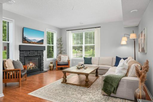 This spacious living room features a gas fireplace and is framed by large windows that fill the space with abundant natural light.