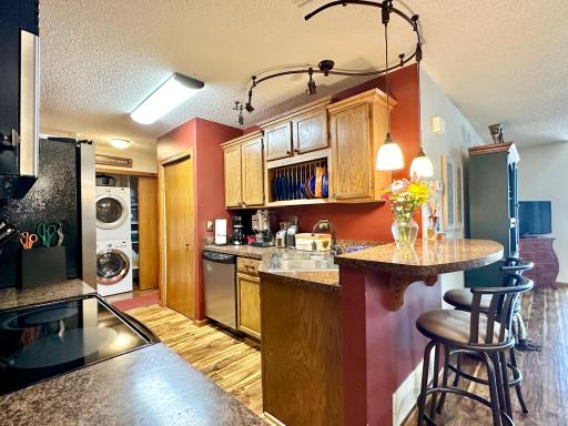 Custom cabinets are highlighted with black and stainless appliances and laminate countertops. Notice the pantry closet next to the dishwasher.