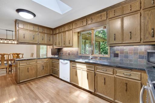 The home's kitchen features oak hardwood flooring, custom cabinets, granite countertops, under cabinet countertop lighting and a gorgeous tile backsplash. The large window above the sink offers fabulous backyard views.