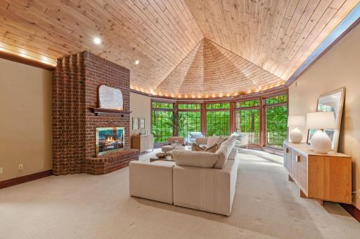 A wall of windows invites natural light to flood the room while framing serene views of the wooded lot.