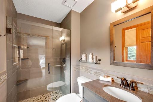 Beautifully updated primary bath with frameless gland shower doors, plus new tile and stone shower, vanity, toilet lighting and fixtures.