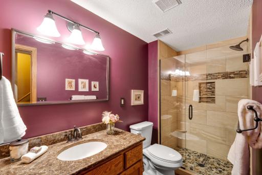 Another update bath in the lower level with stone tile , newer vanity, frameless shower door and lots of storage.