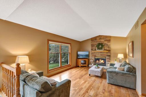 The cozy vaulted family room features newer hickory flooring, a gas fireplace with a stone surround and large windows overlooking the private back yard.