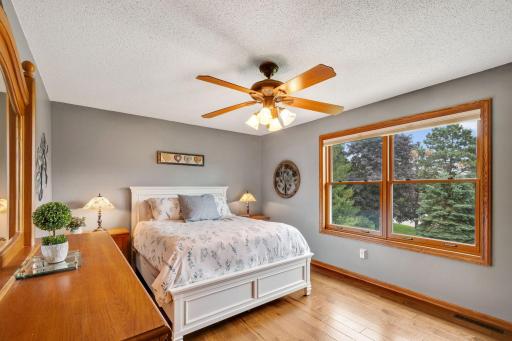 Upper Level Primary suite - more hardwood flooring and views of the private backyard with tall pines.