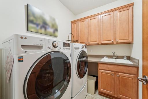 Main floor front load washer and dryer with laundry sink and cabinets.