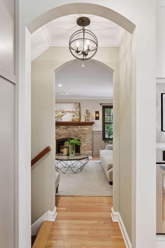 A graceful arched doorway and stylish pendant light frame the view into the sunlit living room
