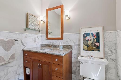 Attached half bath showcases honed marble tiles, classic penny tile flooring, and a backyard-facing window that fills the space with natural light